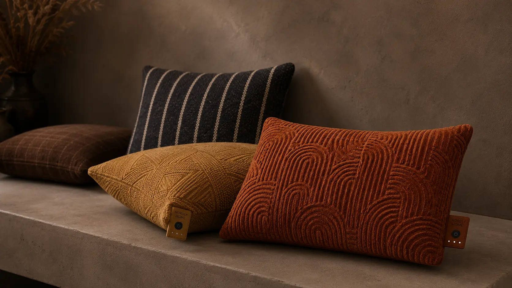 Drie Nordly Home warmtekussens met patronen op een bank